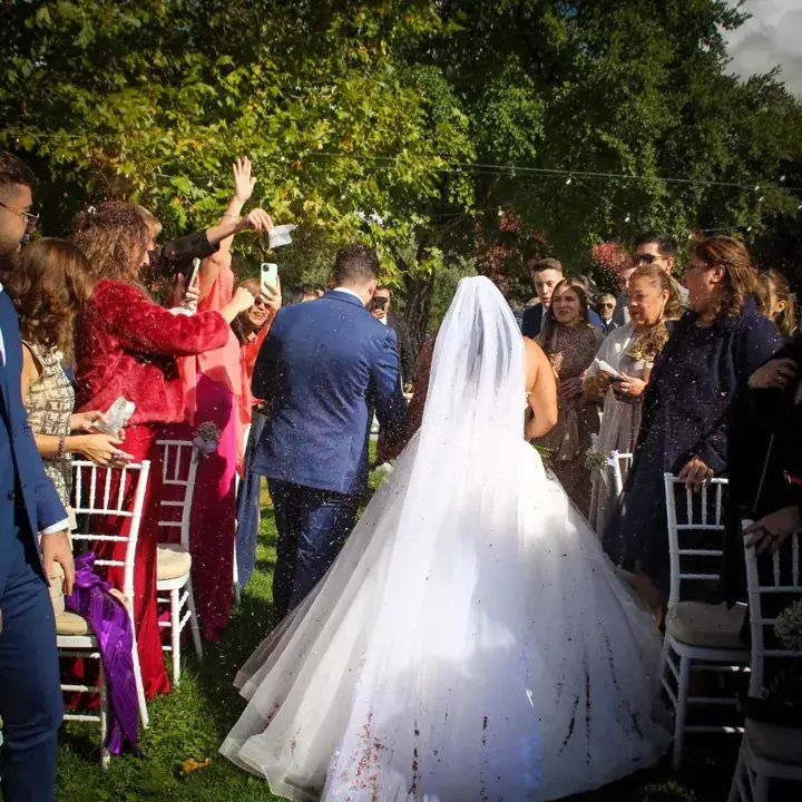 Novia caminando hacia el altar en una ceremonia al aire libre mientras los invitados lanzan pétalos